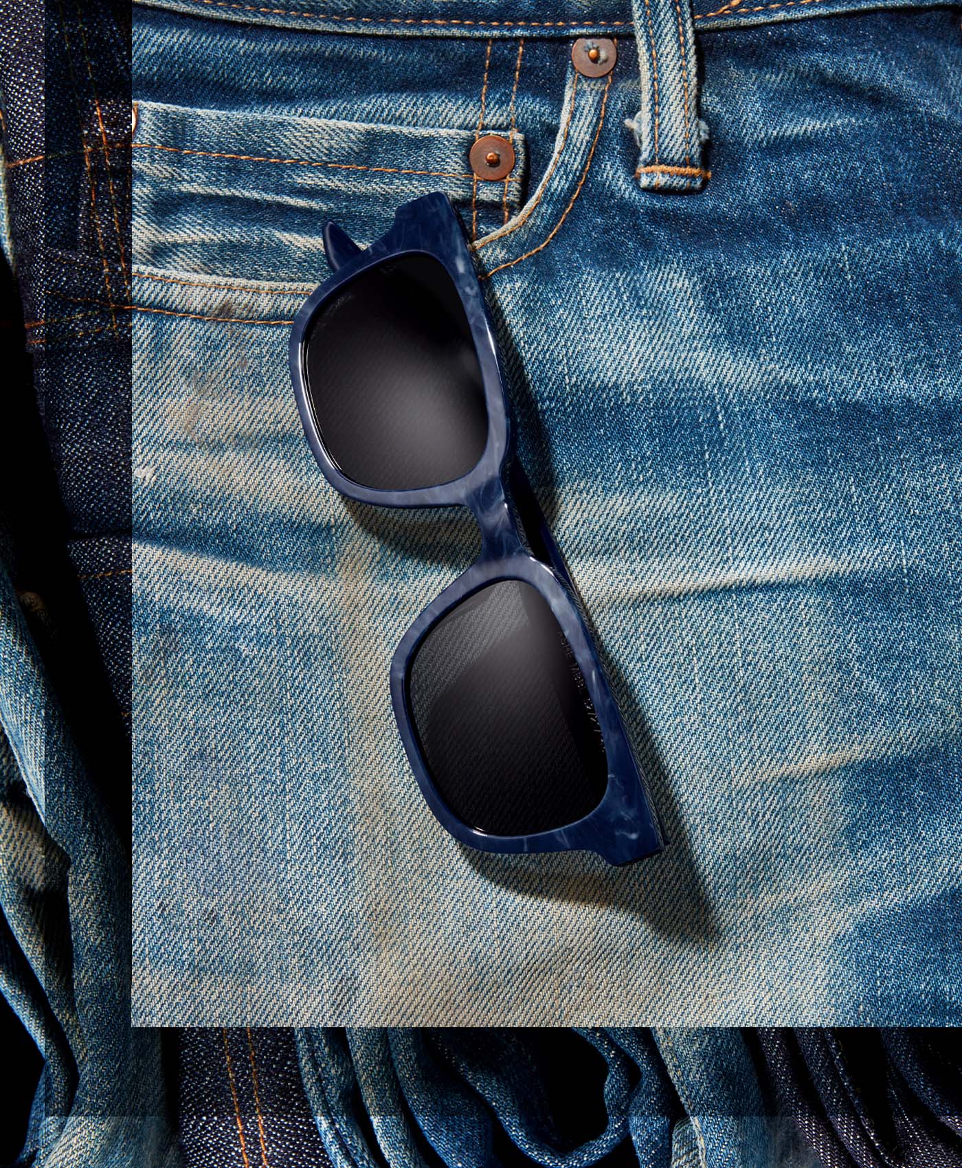 Blue sunglasses on a pair of blue jeans